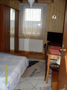 ビャウォヴィエジャにあるU Heleny i Piotra pokoje goscinneのベッドルーム1室(ベッド1台、デスク、窓付)