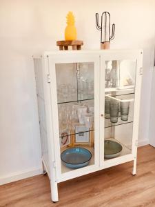a white cabinet with glass doors and a cactus at Vakantiehuis Witsand 1 in Egmond aan Zee