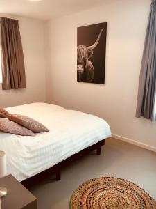 a bedroom with a bed with a picture of a bull on the wall at Vakantiehuis Witsand 1 in Egmond aan Zee