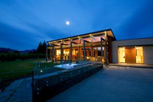 ein großes Glashaus mit Swimmingpool in der Nacht in der Unterkunft Mt Gold Retreat - Sleeps 8 - Spa Pool - Tennis Court in Wanaka
