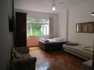 Zimmer mit einem Bett, einem Stuhl und einem Fenster in der Unterkunft FLAT 201 in Petrópolis
