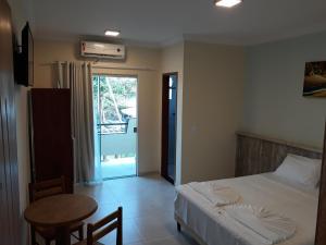 a bedroom with a bed and a table and a window at Areia do Atlantico Hotel in Porto Seguro
