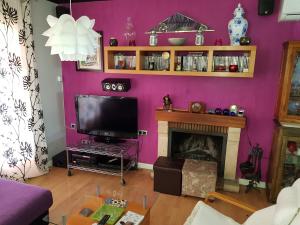 sala de estar con pared de color púrpura y TV en Casa en Peligros cerca de Granada, en Peligros