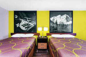 two beds in a room with yellow walls at Super 8 by Wyndham Prattville Montgomery in Prattville
