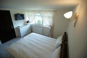a bedroom with a white bed and a window at Casa de vacanța La Mamuca in Colibiţa
