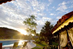 vistas a una piscina con sillas y palmeras en Canto de Roca Turismo e Lazer, en Mimoso do Sul
