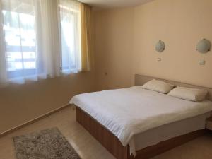 a bedroom with a bed with white sheets and a window at Apartment Lucy in Pamporovo
