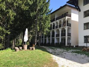 a large white building with a umbrella in the yard at Apartment Lucy in Pamporovo