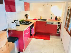 a kitchen with red cabinets and a stove top oven at Le gîte des écureuils in Schalkendorf