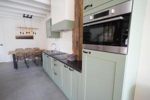 a kitchen with white cabinets and a stove top oven at 't Veldehof in Domburg