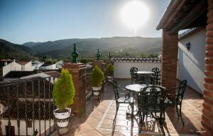a balcony with tables and chairs and a view of mountains at Casa Grande de El Burgo in El Burgo