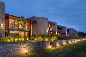 a house with a stone wall and lights at Hotel Aretê in Búzios