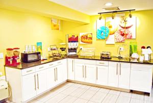 una cocina con armarios blancos y una pared amarilla en Flagship Inn & Suites, en Groton