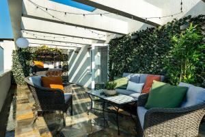a patio with chairs and a table and a hedge at Qult - Up in the Sky in Bucharest
