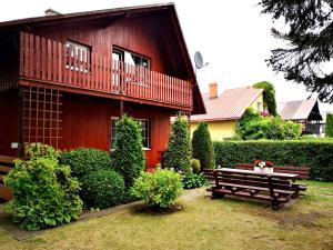ein rotes Haus mit einer Bank davor in der Unterkunft Rowianka in Rowy