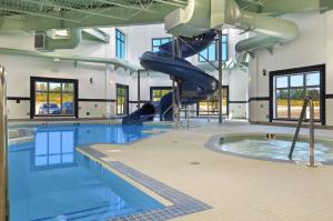 a large swimming pool with a slide in a building at Ramada by Wyndham Lac La Biche in Lac La Biche