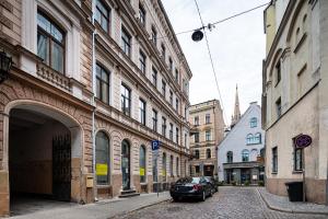 eine Stadtstraße mit Gebäuden und einem Auto auf der Straße in der Unterkunft Old Riga Quiet Apartment in Riga