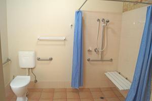 a shower stall with a toilet and a shower curtain at Emeraldene Inn & Eco-Lodge in Hervey Bay