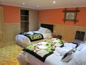 two beds in a room with orange walls at Patagonia Swiss House in Puerto Natales