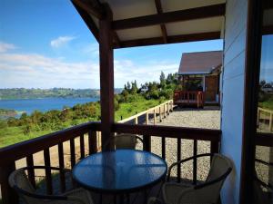 einen Tisch und Stühle auf einem Balkon mit Blick auf das Wasser in der Unterkunft Terrazas de Nercon in Castro