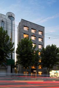 a tall gray building with trees in front of it at Hostel CLEO Seoul Hongdae in Seoul