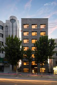 a tall building with trees in front of it at Hostel CLEO Seoul Hongdae in Seoul