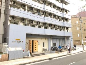 two people riding bikes in front of a building at Hotel Mirai in Yokohama