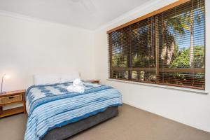 a bedroom with a bed with a teddy bear on it at Breeze@Byron 1 Clarkes Beach in Byron Bay