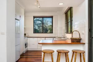 a kitchen with wooden stools at a kitchen island at Breeze@Byron 1 Clarkes Beach in Byron Bay