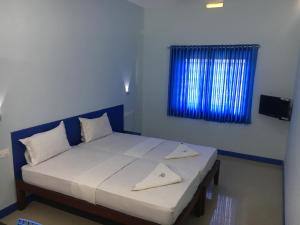 Bett in einem Zimmer mit blauem Fenster in der Unterkunft Kalluvalappil Holiday Inn in Kasaragod