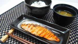 a black plate with a piece of fish and a bowl of soup at Hotel Atlantis Higashi Osaka (Adult Only) in Osaka