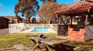 a picnic table with a laptop on it next to a pool at Alfred Motor Inn in Ballarat