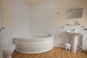 a bathroom with a tub and a toilet and a sink at All Seasons Lodge Hotel in Great Yarmouth