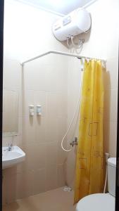 a bathroom with a shower with a yellow shower curtain at Womy Homy in Bogor