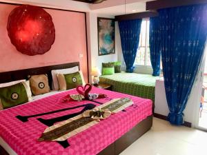 een slaapkamer met een roze en groen bed met lint bij Casa E Mare in Kata Beach