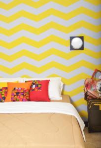 1 dormitorio con una pared de rayas amarilla y blanca en Cihampelas Homestay, en Bandung