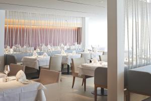 ラドルフツェル・アム・ボーデンゼーにあるホテル ボラ ホットスパリゾートの白いテーブルと椅子、大きな窓のあるレストラン