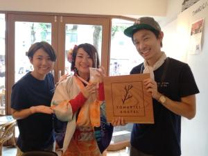 eine Gruppe von drei Personen, die ein Zeichen halten in der Unterkunft Tomarigi Hostel Cafe Bar in Kōchi