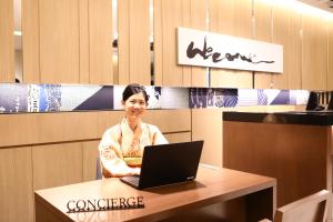 a woman sitting at a table with a laptop at Hotel Gracery Asakusa in Tokyo