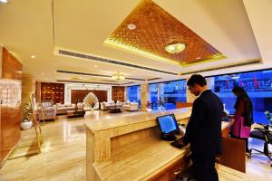 a man standing at a counter in a lobby with a laptop at Regenta Central Srinagar, Rajbagh in Srinagar