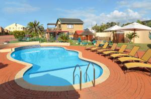 uma grande piscina com cadeiras e um guarda-sol em First Group Club Hacienda em Shelly Beach