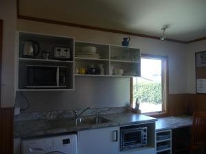 a kitchen with a sink and a microwave at 49 on Jans Beach Break in Oakura