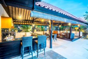 un patio al aire libre con un bar con sillas azules en Gili Villas en Gili Trawangan