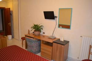Cette chambre dispose d'un bureau, d'une télévision et d'un miroir. dans l'établissement La Villa dei Gourmets - Struttura Sanificata, à Foggia