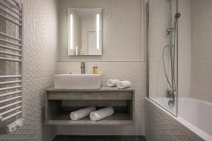 ein Badezimmer mit Waschbecken, Spiegel und Badewanne in der Unterkunft SOWELL HOTELS Les Chevaliers in Carcassonne + 77 Fotos