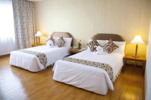 una habitación de hotel con dos camas con animales de peluche. en Thumrin Thana Hotel, en Trang