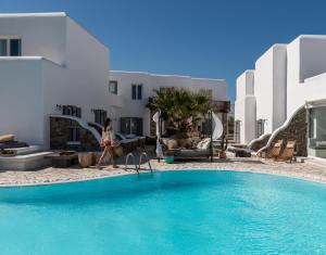 a woman walking by a swimming pool in a hotel at A Hotel Mykonos in Mýkonos City