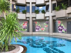 プーケットタウンにあるI Pavilion Hotel Phuketの建物の横に花が咲くホテルのスイミングプール