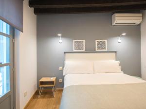 トレドにあるAldaba Apartamentosの白いベッドとテーブルのある寝室