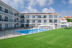 a large building with a swimming pool in front of it at Cerca da Vitoria 3 Milfontes in Vila Nova de Milfontes